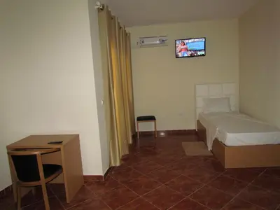 a bedroom with a bed and a table and a tv at Residêncial Carlos Carvalho in Praia