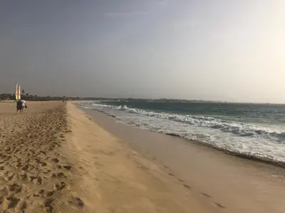 a beach with a person walking on the sand at Oceanfront Apt 4 Porto Antigo II in Santa Maria