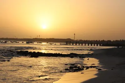 a sunset over a beach with a pier at Oceanfront Apt 4 Porto Antigo II in Santa Maria