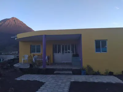 a yellow house with a mountain in the background at Ciza e Rose in Portela