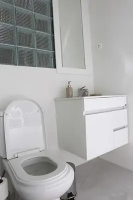 a white bathroom with a toilet and a sink at Sonho Appartement in Praia
