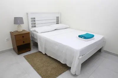a bedroom with a white bed and a nightstand with a blue towel at Apartamento Micael in Praia