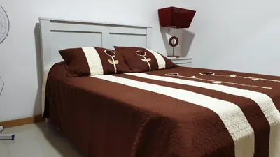 a bed with a brown and white blanket and pillows at Jessica Appartment in Praia