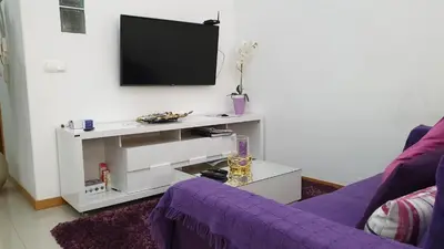 a living room with a purple couch and a tv at Jessica Appartment in Praia