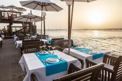 a restaurant with tables and umbrellas next to the water at Hotel Odjo d'água in Santa Maria