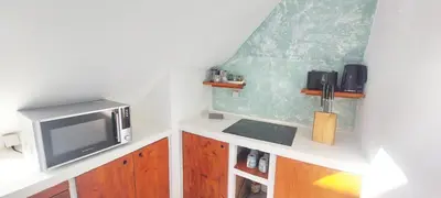a small kitchen with a microwave and a tv at Penthouse with rooftopbar, Fiber WiFi, next to the beach! in Santa Maria