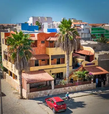 a red car parked in front of a building with palm trees at Sakaroule B&B in Santa Maria
