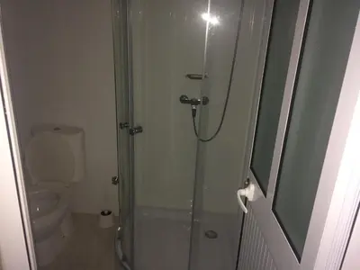 a bathroom with a glass shower with a toilet at Pensao Motel Sodade in São Filipe