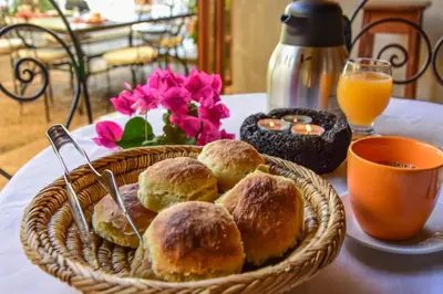 a basket of pastries on a table with orange juice and flowers at Casa Colonial Koenig in São Filipe