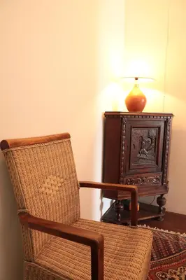a chair and a table with a lamp and a small cabinet at Casa Colonial Koenig in São Filipe
