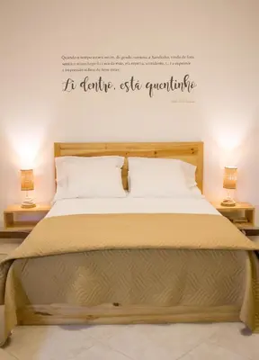 a bed in a room with two lamps and words on the wall at Apartamento Xandinha Amwilla Guesthouse in Mindelo