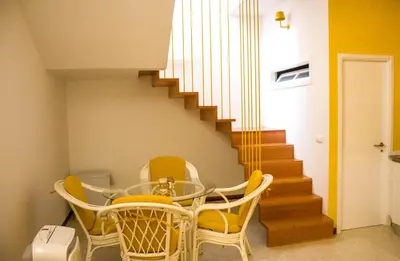 a dining room with a glass table and yellow chairs at Apartamento Xandinha Amwilla Guesthouse in Mindelo