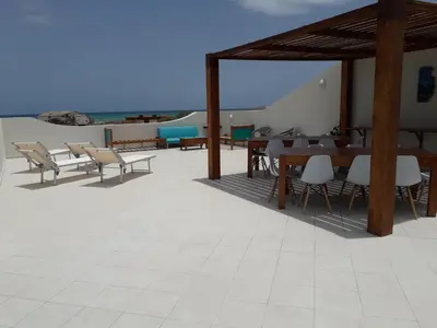 a patio with tables and chairs on the beach at B&B Sereia Azul Boa Vista in Sal Rei