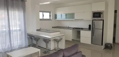 a kitchen with a counter and a sink and a refrigerator at Apartamentos DECOR in Tarrafal