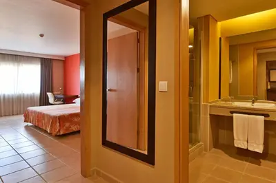 a hotel room with a bathroom with a bed and a sink at Pestana Tropico Ocean & City Hotel in Praia