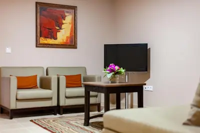 a living room with two chairs and a table with a tv at Pestana Tropico Ocean & City Hotel in Praia