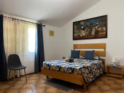a bedroom with a bed and a painting on the wall at Splendid Guest Suite with Separate Private Ocean View Terrace in Praia