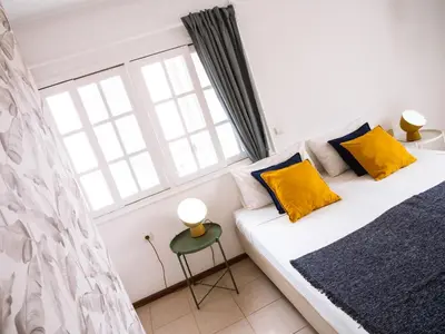 a bedroom with a bed with yellow pillows and a window at Casa Blu Guesthouse - Casa de Hospedes in Santa Maria