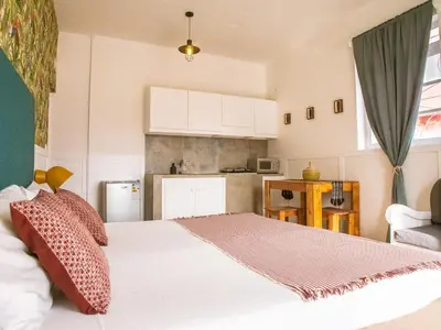 a bedroom with a white bed and a kitchen at Casa Blu Guesthouse - Casa de Hospedes in Santa Maria