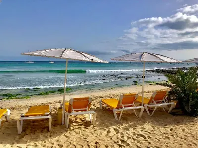 a group of chairs and umbrellas on a beach at Sal&Love apt in Porto Antigo in Santa Maria