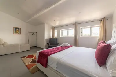 a bedroom with a large white bed and a chair at A Casa da Mizi in Praia