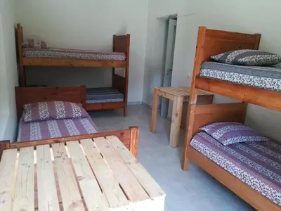 a room with three bunk beds and a wooden table at Casa Pedrina in Ribeira Grande