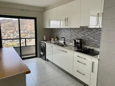 a kitchen with white cabinets and a view of a city at Ocean View Stay in Mindelo