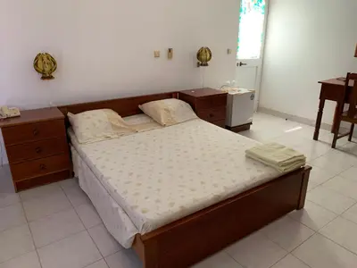 a bedroom with a bed and two dressers and a table at Residencial Pôr do Sol in Porto Novo