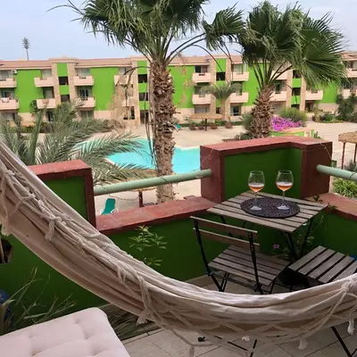 a hammock on a balcony with a table and two glasses of wine at More then a beautiful apart The real Morabeza Capeverdean hospitality in Santa Maria