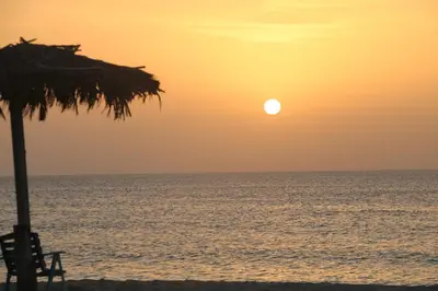 a sunset on the beach with an umbrella and the ocean at Villa Alfredo Marchetti Nº13 A Suites on the Beach, Praia de Chaves, Boa Vista in Cabeçadas