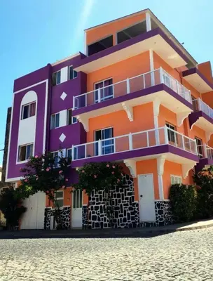 a purple and orange building sitting on top of a beach at Casa Celeste in Ponta do Sol