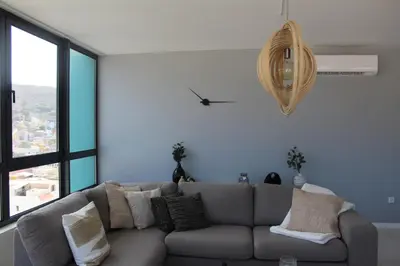 a living room with a gray couch and a large window at Harmony apartment in Mindelo São Vicente in Mindelo