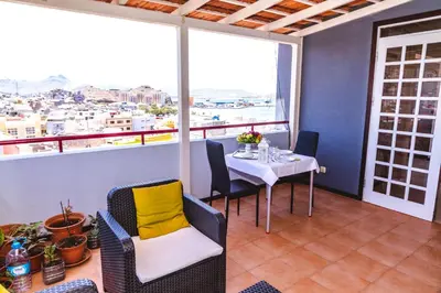 a dining room with a table and chairs and windows at Criola Vistamar in Mindelo