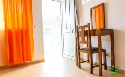 a chair and a mirror in a room with orange curtains at Pousada Green Place in Ribeira Grande