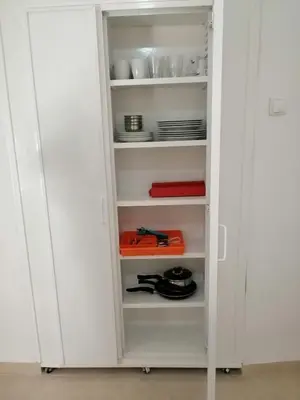 a white pantry with white shelves and dishes at Casas do Cinema I in Mindelo