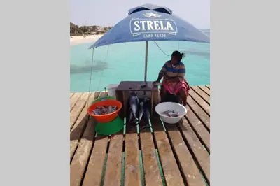 a woman sitting on a table under an umbrella at Schönes, ruhiges und geräumiges Apartment mit Poolanlage in der Nähe von Santa Maria in Prainha