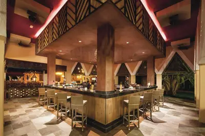 a bar in a restaurant with chairs and a person at Hotel Riu Cabo Verde - Adults Only - All Inclusive in Santa Maria