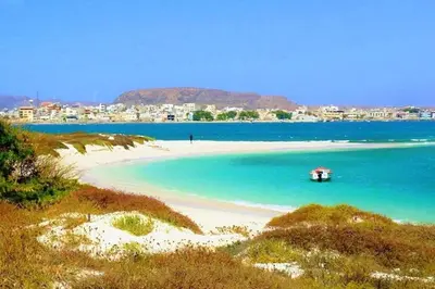 a beach with a small boat in the water at Comfortable and spacious apartment with ocean views of Cabral beach in Sal Rei