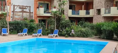 a swimming pool in front of a building with blue chairs at Sal Service djasal residence with pool in Santa Maria