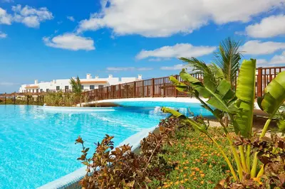 a bridge over a large swimming pool with blue water at Melia Dunas Beach Resort & Spa - All Inclusive in Santa Maria