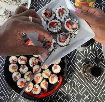 a person cutting a box of sushi with a knife at Palmeira Da Cruz EcoLodge in Chã da Igreja