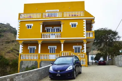 a car parked in front of a yellow building at Residensia Ka Denxu in Vila Nova Sintra