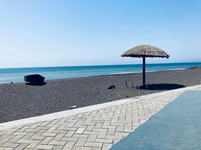 a straw umbrella on a beach with the ocean at Pedra de Rala in Porto Novo