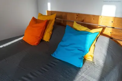 a bed with four colorful pillows on it at Apartamento Zinha Amwilla Guesthouse in Mindelo