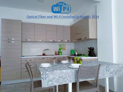 a kitchen with wooden cabinets and a table with chairs at Rosa dei Venti Apartment 50meter beach front in Sal Rei