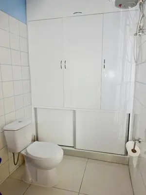 a bathroom with a toilet and white cabinets at Apartment with sea view near the beach and the village center! in Tarrafal