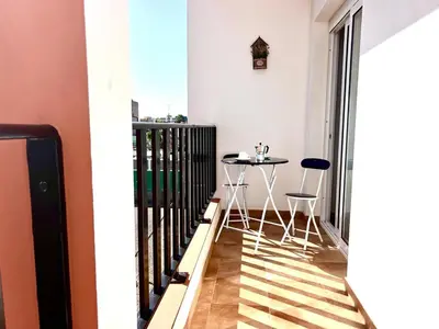 a balcony with a table and two stools at DAISAL APARTMENT - 2 bedroom apartment with balcony near the beach & city center in Santa Maria