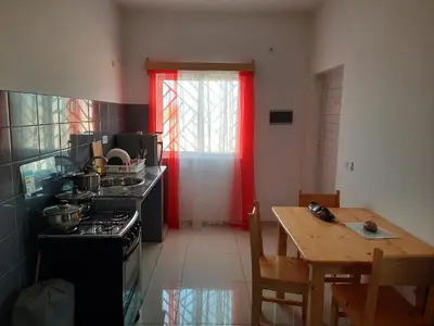 a kitchen with a stove and a table and a red curtain at Guest House Maio in Vila do Maio