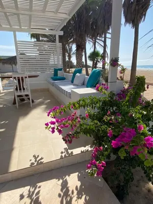 a porch with a couch and flowers on the beach at Villa Nº25b Alfredo Marchetti suites on the beach Praia di Chaves in Cabeçadas