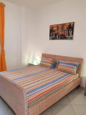 a bed with a striped blanket on top of it at App Raffaele Estoril Beach Free Wifi & AC a step away from the sea in Sal Rei